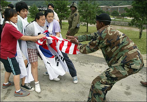 한 미군이 대학생들이 불태우려는 성조기를 뺏으려하고 있다. 